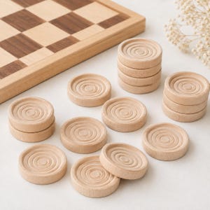 May include: A wooden checkerboard with a light and dark brown square pattern, accompanied by several light-colored wooden game pieces. Each circular piece features a series of concentric rings carved into the top surface, arranged in stacks.
