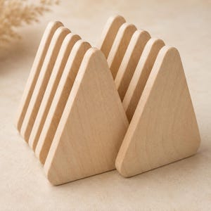 May include: A set of eight light-colored wooden pieces, each shaped as an equilateral triangle with rounded corners. The pieces are arranged in two parallel rows, standing upright on their bases, showcasing a smooth, natural wood grain texture.