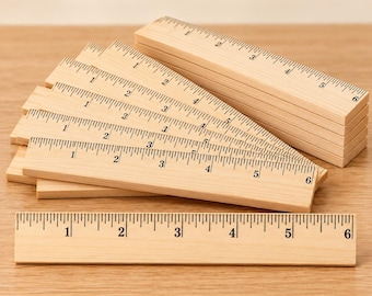 May include: A stack of light-colored wooden rulers, each featuring black printed markings and numbers ranging from one to six inches. The rulers are arranged in a fan-like pattern, with one ruler placed horizontally in the foreground.
