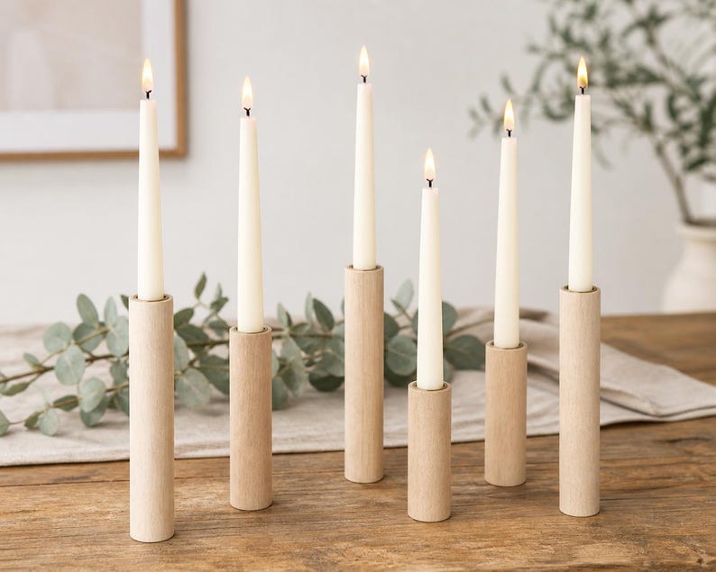 May include: Six tall, slender, off-white taper candles are each set into individual, cylindrical, light-toned wooden candle holders of varying heights. Each candle is lit, producing a small, warm flame at the top of the wax taper.
