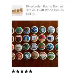 May include: A collection of round wooden ornaments featuring hand-painted illustrations including a crown, a whale, a ram, a shell, a scroll, and various religious symbols. Each circular wooden piece has a small hole at the top for hanging.