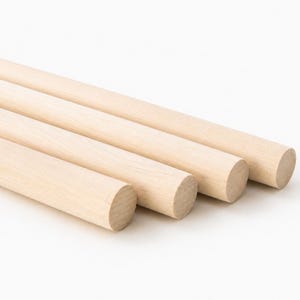 May include: Three cylindrical wooden dowels with a smooth, light beige finish. Each dowel features a uniform, straight shape with circular ends, showcasing the natural grain and texture of the light-colored wood in a simple, parallel arrangement.