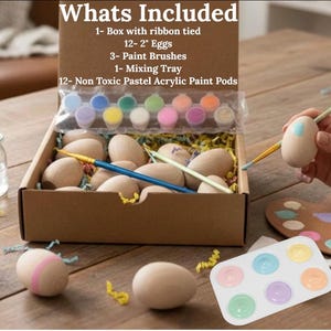 May include: A craft kit with a box containing wooden eggs, paint brushes, and pastel acrylic paint pods. The box includes 12 wooden eggs, each approximately 2 inches in length, and a mixing tray. The text "Whats Included" is at the top.