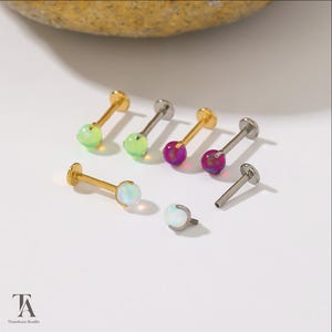 Peut inclure: Une collection de bijoux labret avec des pierres rondes type opale en vert citron, magenta et blanc. Les tiges sont disponibles en finitions métal doré et argenté. Certains bijoux sont assemblés, d'autres montrent la tige filetée.