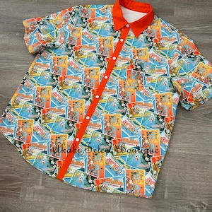 May include: A short-sleeved button-down shirt with a colorful print of postcards featuring Olaf from the movie Frozen. The shirt has a bright orange collar and buttons.