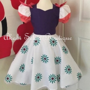 May include: A white dress with a purple bodice and pink and white puffed sleeves. The skirt has a green and white floral pattern. The dress is on a mannequin.