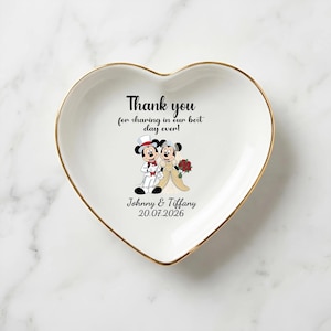 Puede incluir: Plato de cer&aacute;mica blanco en forma de coraz&oacute;n con borde dorado. El plato presenta una imagen de dibujos animados de Mickey y Minnie Mouse con atuendo de boda, con el texto "Thank you for sharing in our best day ever!" y los nombres "Johnny & Tiffany" con la fecha "20.07.2026".