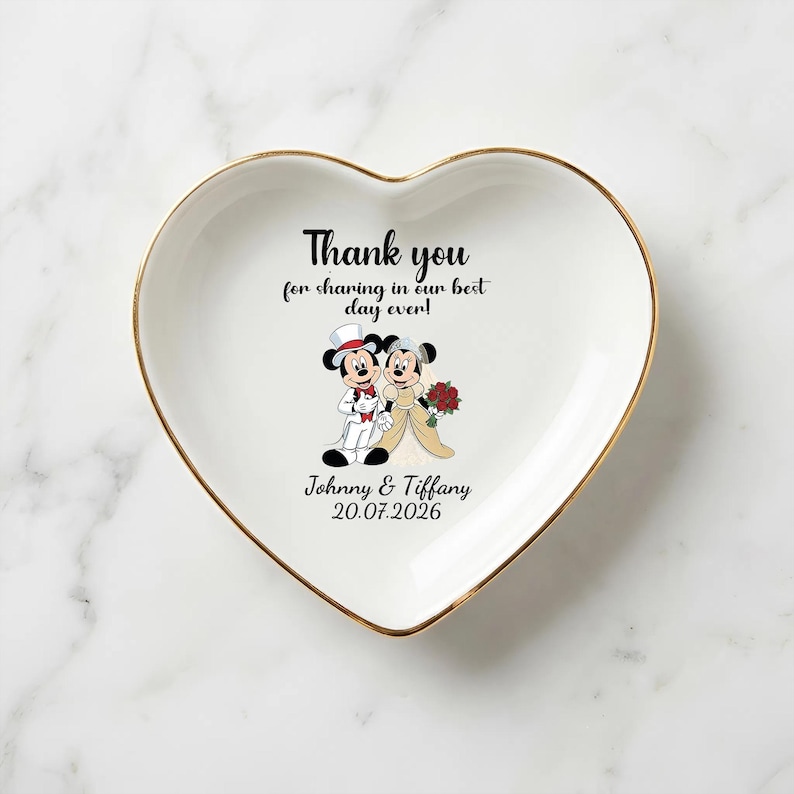 Puede incluir: Plato de cer&aacute;mica blanco en forma de coraz&oacute;n con borde dorado. El plato presenta una imagen de dibujos animados de Mickey y Minnie Mouse con atuendo de boda, con el texto "Thank you for sharing in our best day ever!" y los nombres "Johnny & Tiffany" con la fecha "20.07.2026".