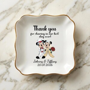 Puede incluir: Un plato de cer&aacute;mica blanco con borde dorado y borde ondulado. El plato presenta una ilustraci&oacute;n de dibujos animados de Mickey y Minnie Mouse con atuendo de boda, con el texto "Thank you for sharing in our best day ever!" y los nombres "Johnny & Tiffany" con la fecha "20.07.2026".