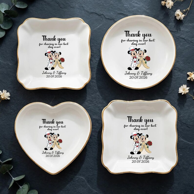 Puede incluir: Cuatro platos de cer&aacute;mica blanca con bordes dorados, cada uno con una forma diferente: cuadrado, redondo, coraz&oacute;n y un cuadrado con bordes festoneados. Cada plato tiene un gr&aacute;fico de boda de Mickey y Minnie Mouse y el texto "Thank you for sharing in our best day ever!" con una fecha.