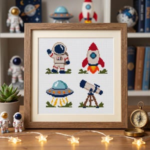 May include: A framed cross-stitch embroidery featuring four space-themed motifs: an astronaut waving, a red and white rocket ship launching, a flying saucer hovering above yellow light beams, and a telescope mounted on a brown tripod stand.
