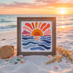 Può includere: Un ricamo a punto croce quadrato in una cornice di legno che raffigura un tramonto stilizzato sopra le onde dell'oceano. Il design mostra un sole arancione brillante con raggi rossi, rosa e arancioni sopra onde blu scuro e azzurre.