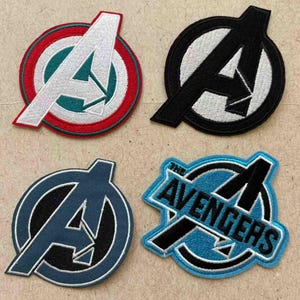 May include: Four embroidered Avengers logo patches. The patches are in different colour schemes: red, white, and green; black and white; navy blue and black; and blue, black, and white with the text "THE AVENGERS".