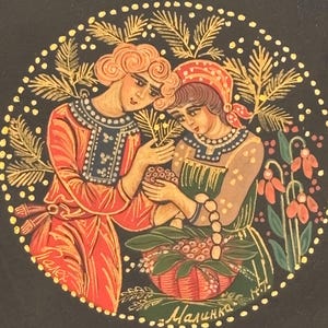 Pode incluir: Uma tampa de caixa de laca preta com uma cena circular pintada à mão de duas figuras em trajes tradicionais colhendo bagas. A obra inclui detalhes dourados, ramos de pinheiro e flores. O texto cirílico lê-se Palekh e Malinka.