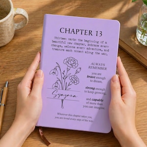 Può includere: Un taccuino viola chiaro con un'illustrazione floreale e il testo: CHAPTER 13, Thirteen marks the beginning of a beautiful new chapter. Embrace every change, welcome every adventure, and treasure each moment along the way. ALWAYS REMEMBER you are brave enough to dream, strong enough to keep growing, and capable of more than you can imagine. Wherever this chapter takes you, you are loved every step of the way. Il nome Syazana è stampato sullo stelo del fiore.