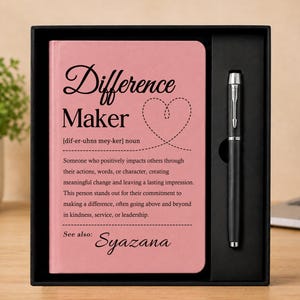 Può includere: Un taccuino rosa con il testo Difference Maker e una definizione stampata in nero, accompagnato da una penna a sfera nera, il tutto in una scatola regalo nera. Il taccuino presenta un contorno a forma di cuore e il nome Syazana in basso.