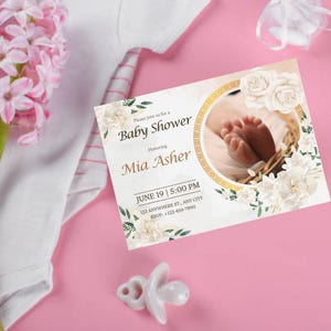 May include: A rectangular baby shower invitation card featuring a circular frame with a photograph of baby feet in a basket. The card includes the text Please join us for a Baby Shower Honoring Mia Asher JUNE 19 | 5:00 PM 123 ANYWHERE ST., ANY CITY RSVP: +123-456-7890.