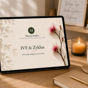 Könnte beinhalten: Ein Tablet mit einem beigen Bildschirm, auf dem der Text Morina Studio, IVF & Zyklus und Dein ruhiger Begleiter auf dem Weg zu sehen ist. Der Bildschirm zeigt ein dunkelgrünes kreisförmiges Logo mit einem M und einen Zweig mit zwei rosa Magnolien.