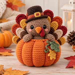 Peut inclure: Une figurine de dinde au crochet portant un chapeau marron avec une boucle jaune, assise dans une grosse citrouille orange. La dinde a un corps marron, des yeux noirs, des joues roses et un éventail de plumes colorées dans les tons rouge, jaune et marron.