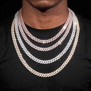 Puede incluir: Cuatro cadenas de eslabones cubanos superpuestas en tonos oro, plata y oro rosa. Cada cadena presenta un diseño de eslabones planos entrelazados con un acabado pulido y reflectante. Los collares están dispuestos en cascada alrededor del cuello.