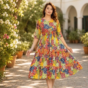 Puede incluir: Un vestido hasta la rodilla con un vibrante patrón de retazos de motivos florales y de cachemira en rojo, amarillo, azul y verde. La prenda tiene cuello en V, mangas tres cuartos y una cintura con cordón que crea una falda escalonada.