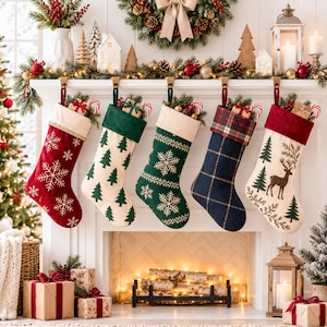 Puede incluir: Cinco calcetines de Navidad colgados de una repisa de chimenea blanca. Los calcetines presentan varios diseños, incluyendo copos de nieve blancos sobre rojo, pinos verdes sobre crema, copos de nieve blancos sobre verde, cuadros azules y un ciervo.