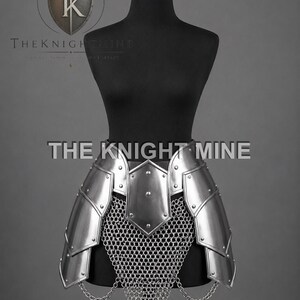 May include: Silver metal armour skirt with chainmail and decorative chain accents. The armour is displayed on a black mannequin. The text "THE KNIGHT MINE" is visible.