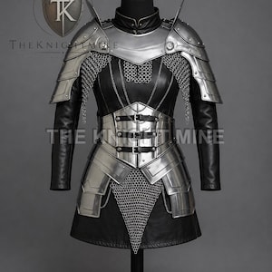 May include: A full suit of armour displayed on a mannequin. The armour is silver-coloured metal and black leather, with chainmail accents. The design includes shoulder pauldrons, a breastplate, and a waist belt. The text "THE KNIGHT MINE" is visible.