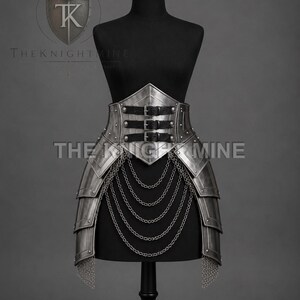 May include: A metallic silver waist armour piece featuring a pointed front panel, three black leather straps with metal buckles, and layered tassets. Five draped silver chains hang from the front, and chainmail accents hang from the sides.