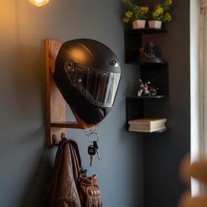 Peut inclure: Un casque de moto noir est suspendu à un support mural en bois, avec une veste et des gants en cuir marron en dessous. Des clés sont accrochées au support. Le casque a une visière transparente.