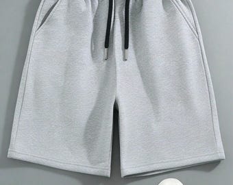 Pantalones cortos deportivos negros para niño, cintura elástica, bolsillos con cremallera, ropa deportiva.
