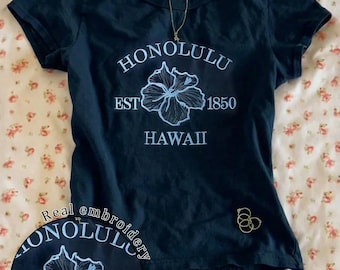 Camiseta azul marino con estampado floral hawaiano y letras, hibisco bordado, top casual de verano.