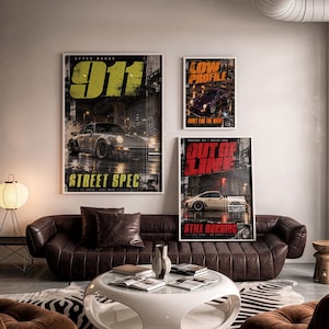 May include: Three framed wall posters featuring sports cars in urban night settings. The largest poster displays a silver car with the text 911 STREET SPEC. A smaller poster shows a purple car with LOW PROFILE, and another shows a white car with OUT OF LINE.
