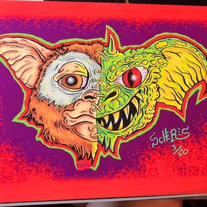 Puede incluir: Ilustración dividida de un Gremlin y un Mogwai. El lado izquierdo es un Mogwai marrón con la cara cosida, y el lado derecho es un Gremlin verde con dientes afilados. La obra de arte está sobre un fondo morado con un borde rojo.