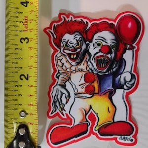 Könnte beinhalten: Ein rot-weißer Clown mit einem roten Ballon. Der Clown hat einen gruseligen Ausdruck und scharfe Zähne. Der Clown trägt ein rot-gelbes Kostüm und rote Schuhe. Der Clown hält einen roten Ballon in seiner rechten Hand. Der Clown steht auf einem weißen Hintergrund. Der Text "SHERESAB" ist in der unteren rechten Ecke des Bildes gedruckt.