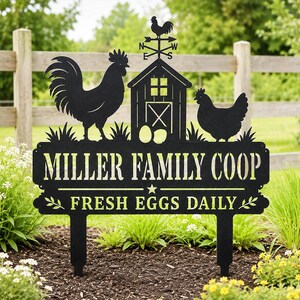 May include: A black metal garden sign featuring a rooster, a hen, and a barn with a weather vane. The text reads MILLER FAMILY COOP and FRESH EGGS DAILY. The sign has two stakes for ground insertion and displays a cutout design of two eggs.