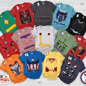 May include: A collection of fourteen short-sleeved t-shirts featuring various superhero-inspired graphic prints. Each shirt displays a unique costume design, including colors like red, green, blue, yellow, black, and gray, with numbered labels from 1 to 14.
