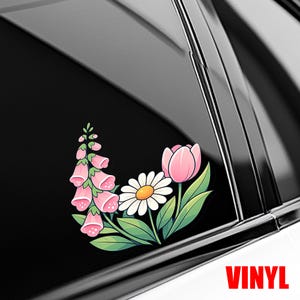 May include: A vinyl decal featuring a cluster of botanical illustrations including a tall stalk of pink foxglove flowers, a single white daisy with a yellow center, and a pink tulip, all surrounded by green leaves, applied to a dark window.