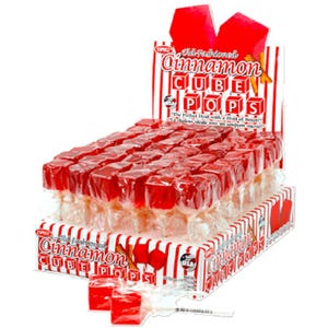 May include: A display box of individually wrapped red Cinnamon Cube Pops candies. The box features red and white stripes and the text "Old Fashioned Cinnamon Cube Pops". The candies are a vibrant red color and appear to be cube-shaped.