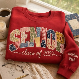 May include: A red crewneck sweatshirt featuring the word SENIOR in large, multi-patterned floral and gingham fabric applique letters. Below the word, the text class of 2027 is embroidered in white. The sleeve features the text custom text.