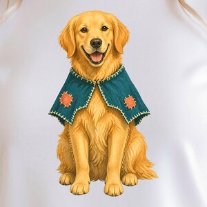 May include: A white t-shirt featuring a graphic illustration of a golden retriever dog sitting upright. The dog has golden fur, an open mouth, and is wearing a dark teal cape with visible light-colored stitching and two orange square patches.
