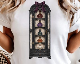 May include: A white t-shirt featuring a graphic print of a tall, dark, ornate cabinet with a purple bow at the top. The cabinet has five shelves, each displaying a uniquely shaped, colorful glass potion bottle with celestial symbols.