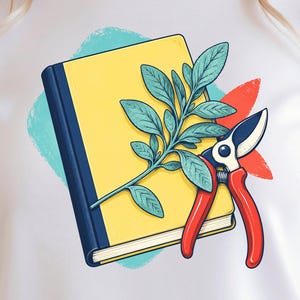 May include: A white t-shirt featuring a graphic illustration of a yellow book with a dark blue spine, a green leafy plant sprig resting on the cover, and a pair of red and black pruning shears positioned next to the book against a teal splash.