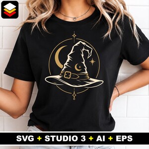 Op de afbeelding: Zwart t-shirt met een gouden heksenhoedontwerp in een cirkel, met een maan en sterren. De tekst "SVG + STUDIO 3 + AI + EPS" staat onderaan. Het ontwerp is waarschijnlijk voor Halloween of een vergelijkbaar thema.