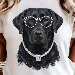 May include: A white t-shirt featuring a graphic print of a black Labrador retriever wearing round, black and white striped glasses and a silver-toned necklace with a large, rectangular, clear gemstone pendant centered at the base of the neck.