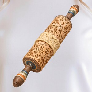 May include: A wooden rolling pin featuring an intricate embossed pattern of Easter eggs, carrots, and animal paw prints. The handles are decorated with horizontal bands of orange, green, and blue, and the central barrel has a lighter wood tone.