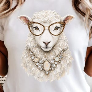 May include: A white t-shirt featuring a graphic print of a sheep wearing leopard print cat-eye glasses and a large, ornate statement necklace made of clear, faceted crystals and a central oval stone, rendered in a textured, painterly art style.
