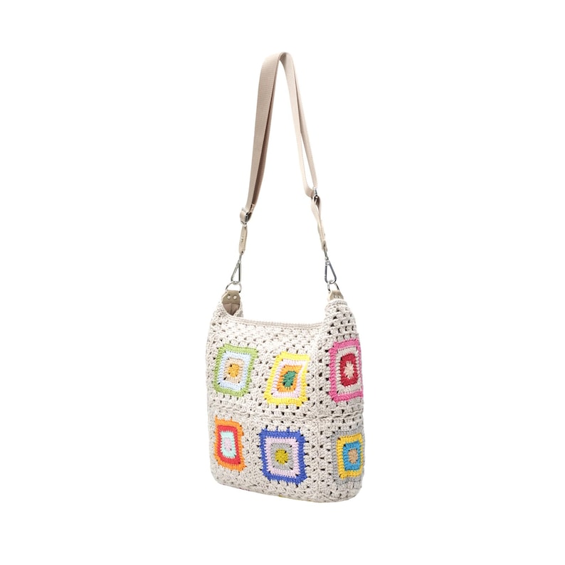 K&ouml;nnte beinhalten: Cremefarbene H&auml;keltasche mit beigem Schulterriemen. Die Tasche hat bunte quadratische Muster in Rot, Orange, Gelb, Gr&uuml;n, Blau und Rosa. Die Tasche hat eine rechteckige Form und einen langen Riemen.
