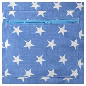May include: Close-up of a blue fabric with a white star pattern. A light blue zippered pocket is sewn onto the fabric. The zipper is light blue and the stitching is white.