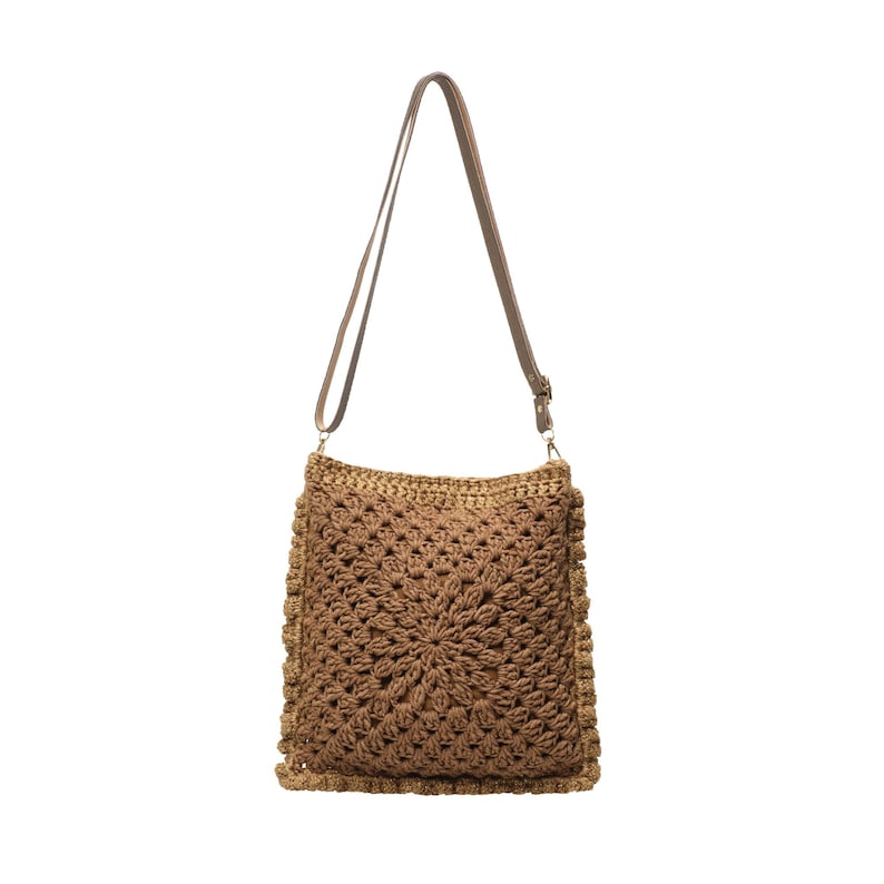 May include: A square-shaped crochet shoulder bag in a medium brown yarn featuring a textured, radiating starburst pattern. The bag includes a thin, adjustable brown strap attached with metal hardware at the top corners of the square body.